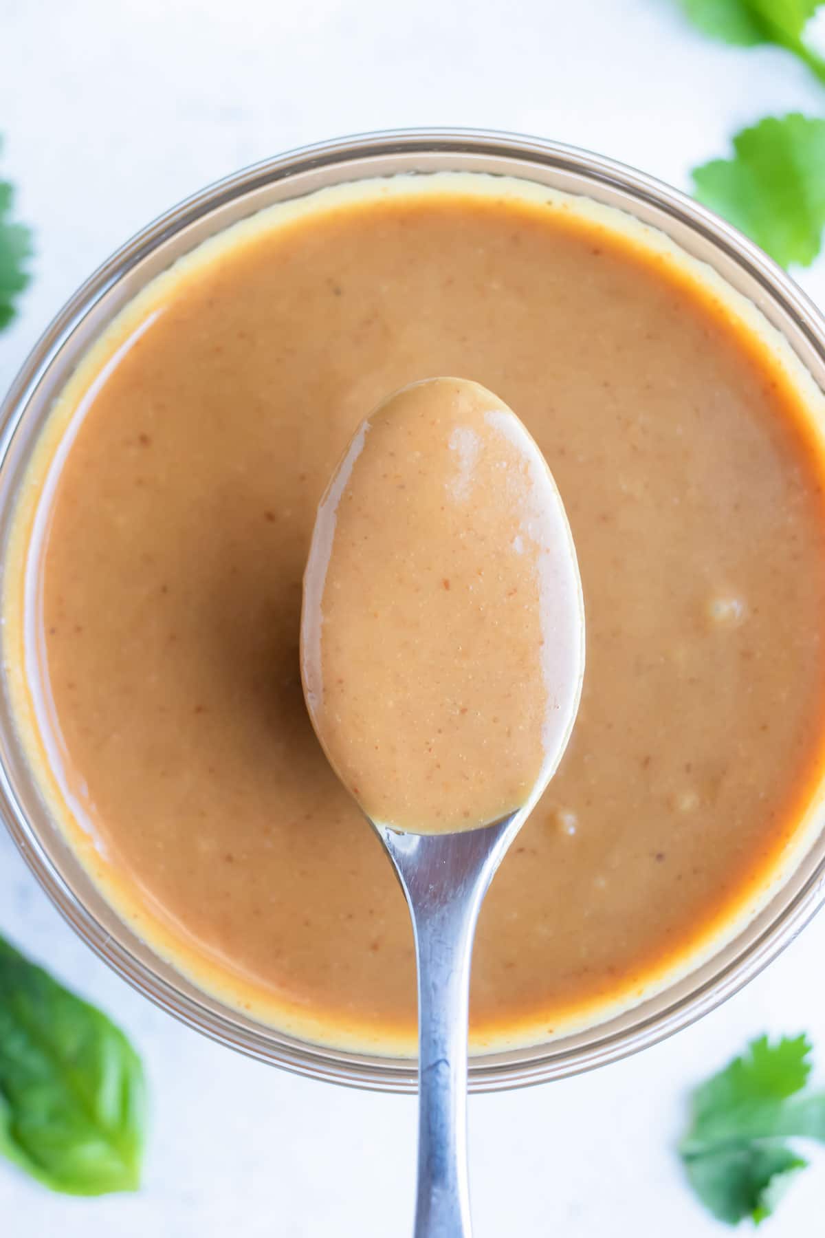 Easy peanut dipping sauce is lifted up with a spoon.