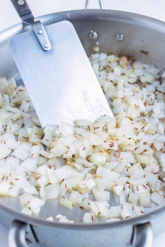 Diced onion is sautéed on the oven in a pan.