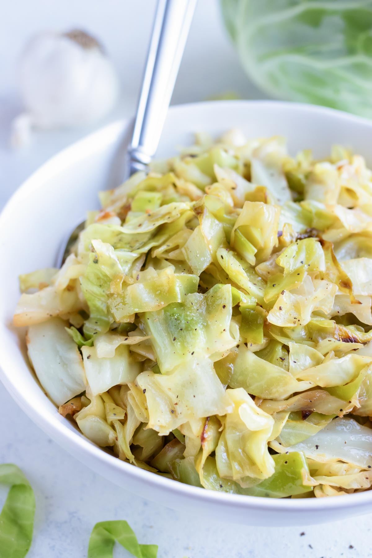 Sautéed cabbage is served with a spoon in a bowl.