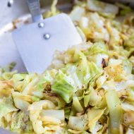 The caramelized, sautéed cabbage is stirred with a spatula.