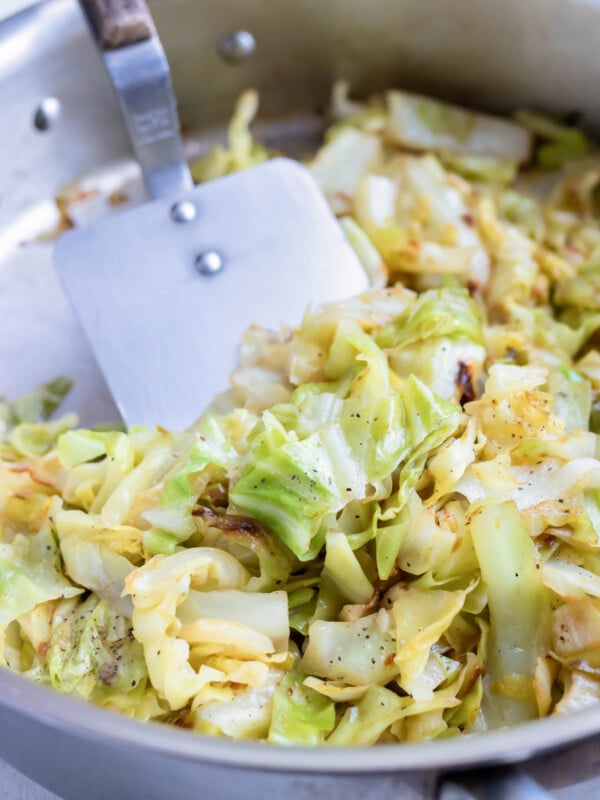 The caramelized, sautéed cabbage is stirred with a spatula.