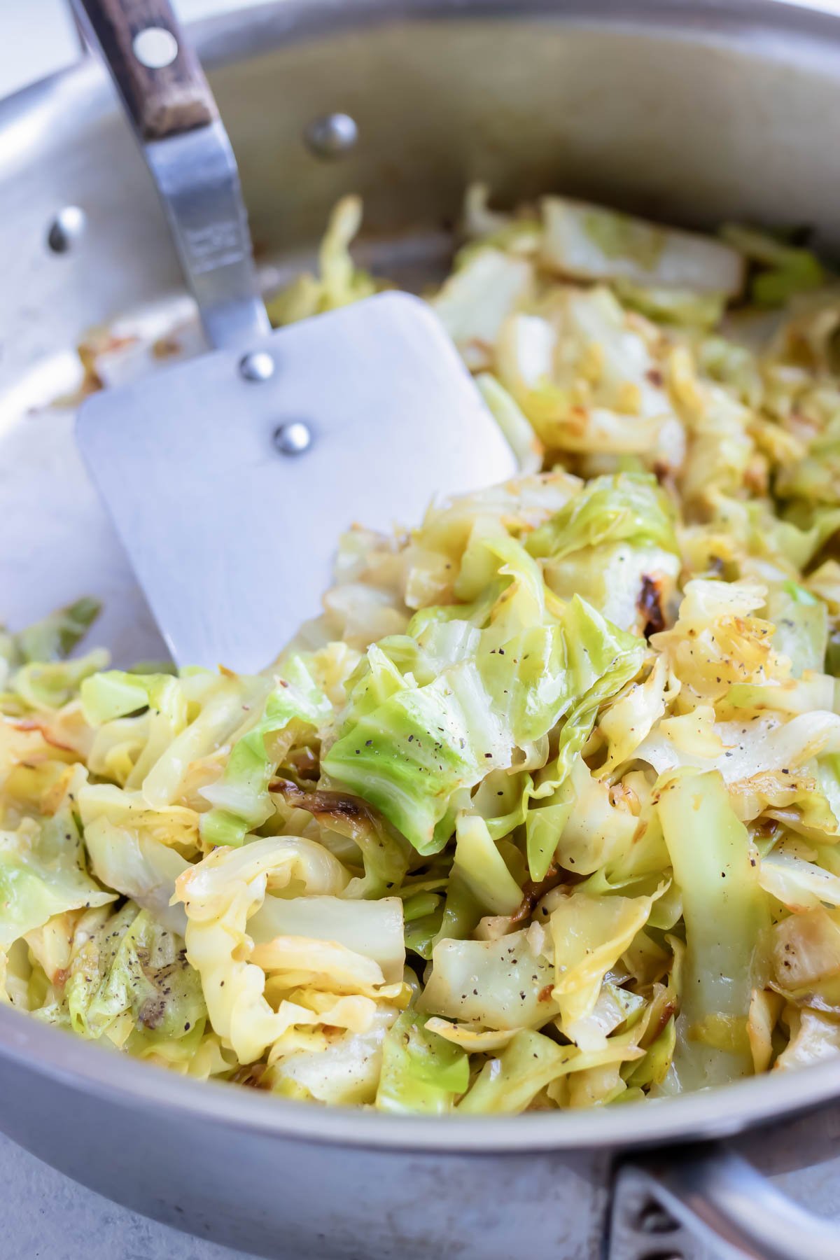 Simple Sautéed Cabbage in a pan with a spatula.