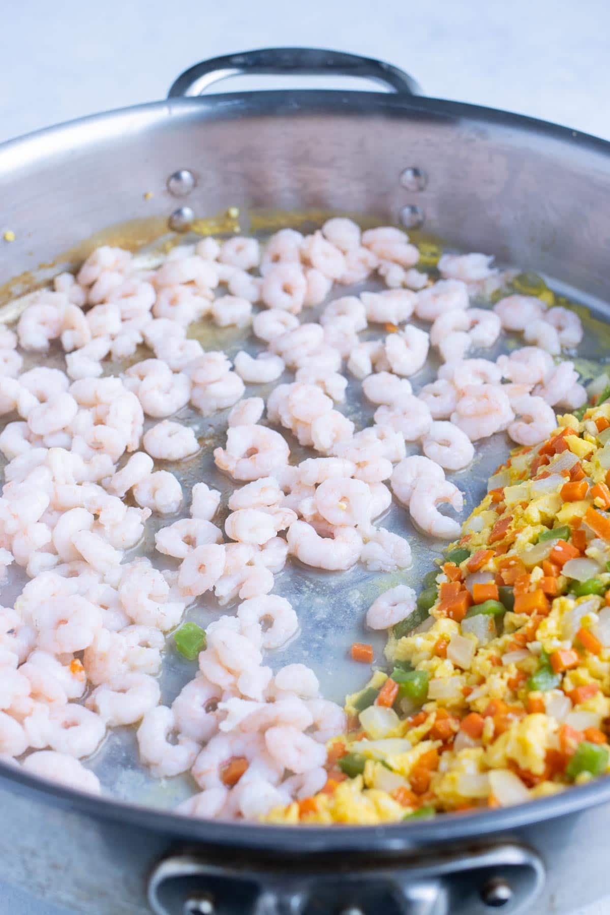Shrimp is added to one side of the skillet.