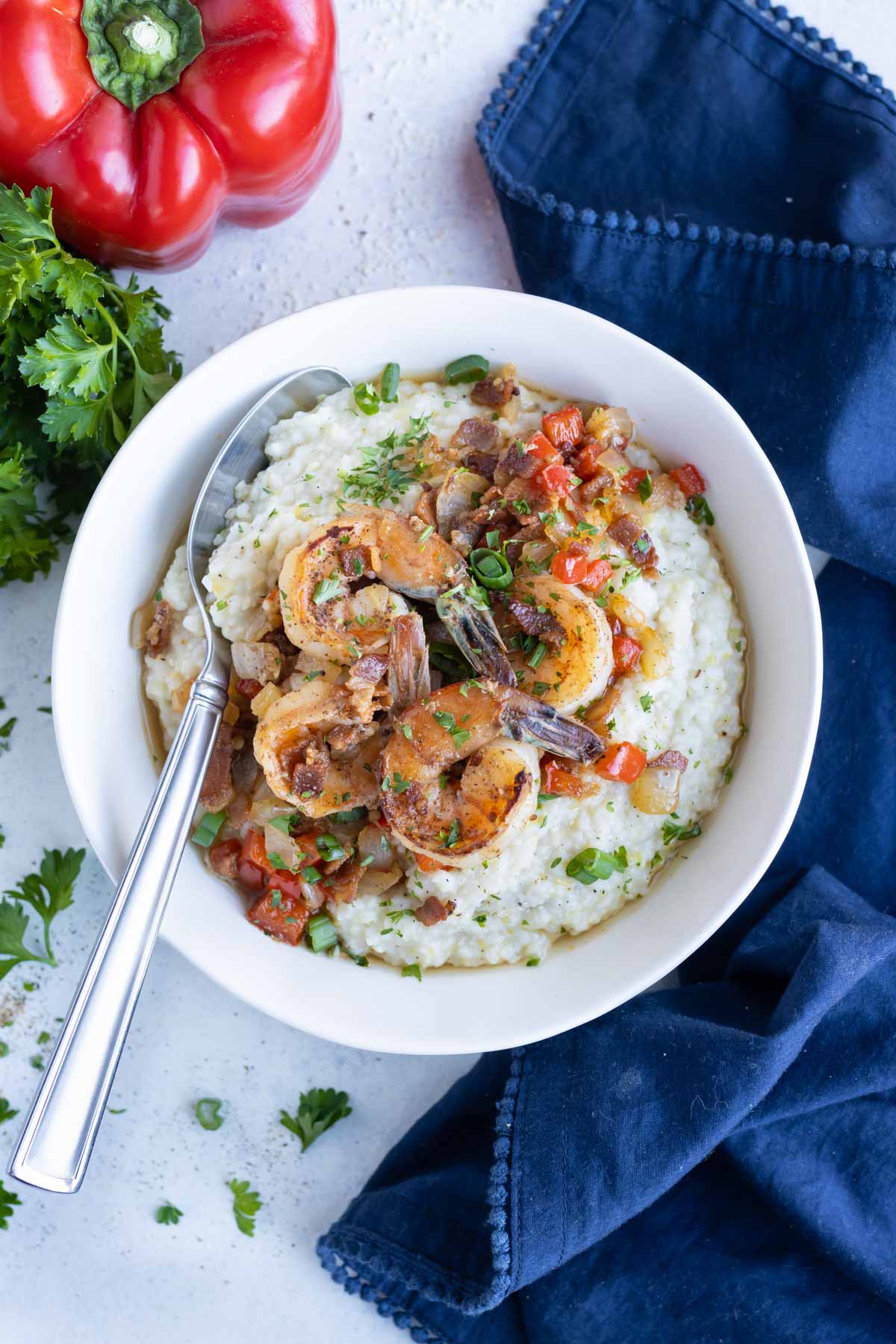 Parsley and chopped green onions are put on top of these Cajun shrimp and grits.