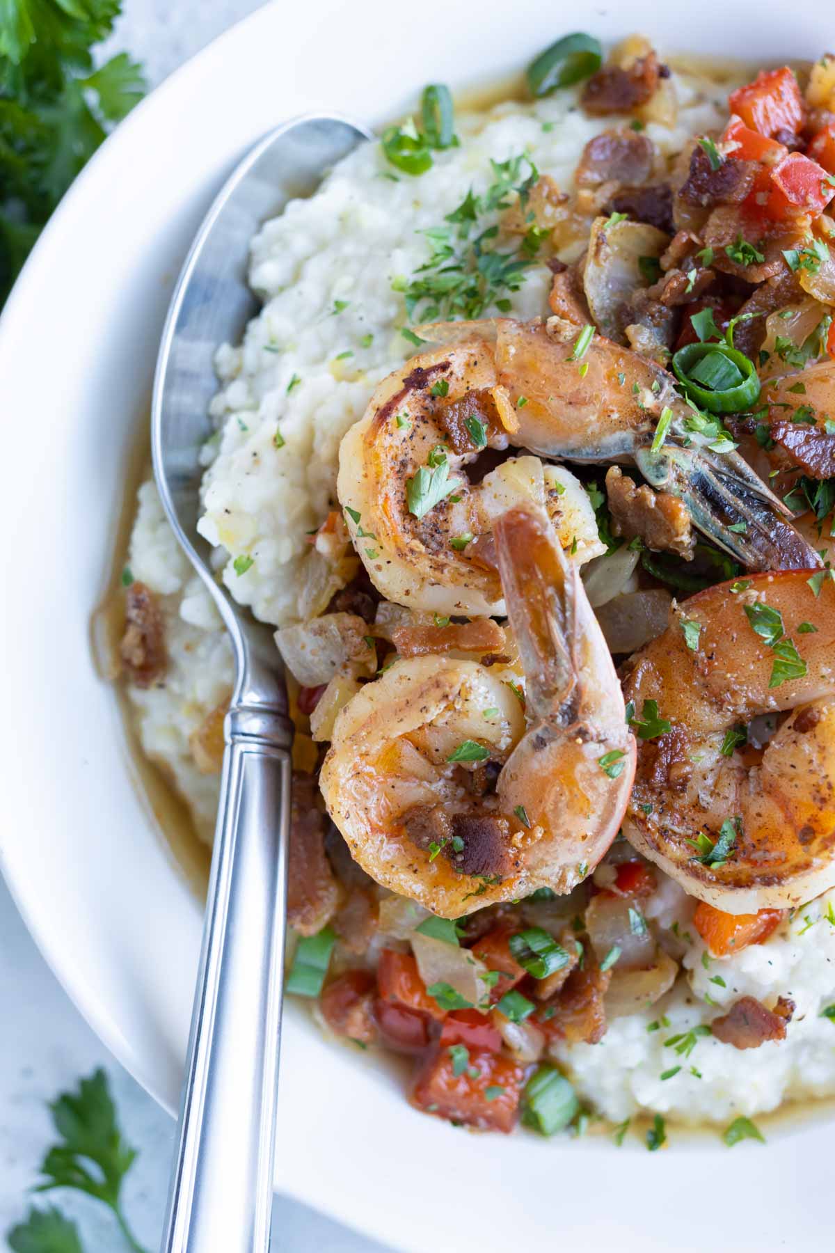 Easy Cajun shrimp and grits is eaten with a spoon from a bowl.