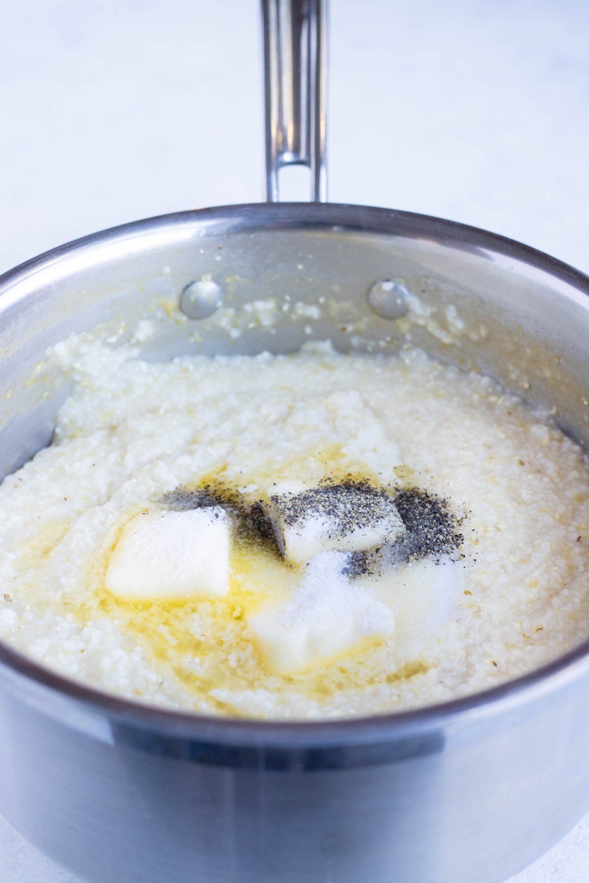 Grits and seasonings are cooked with butter on the stove.