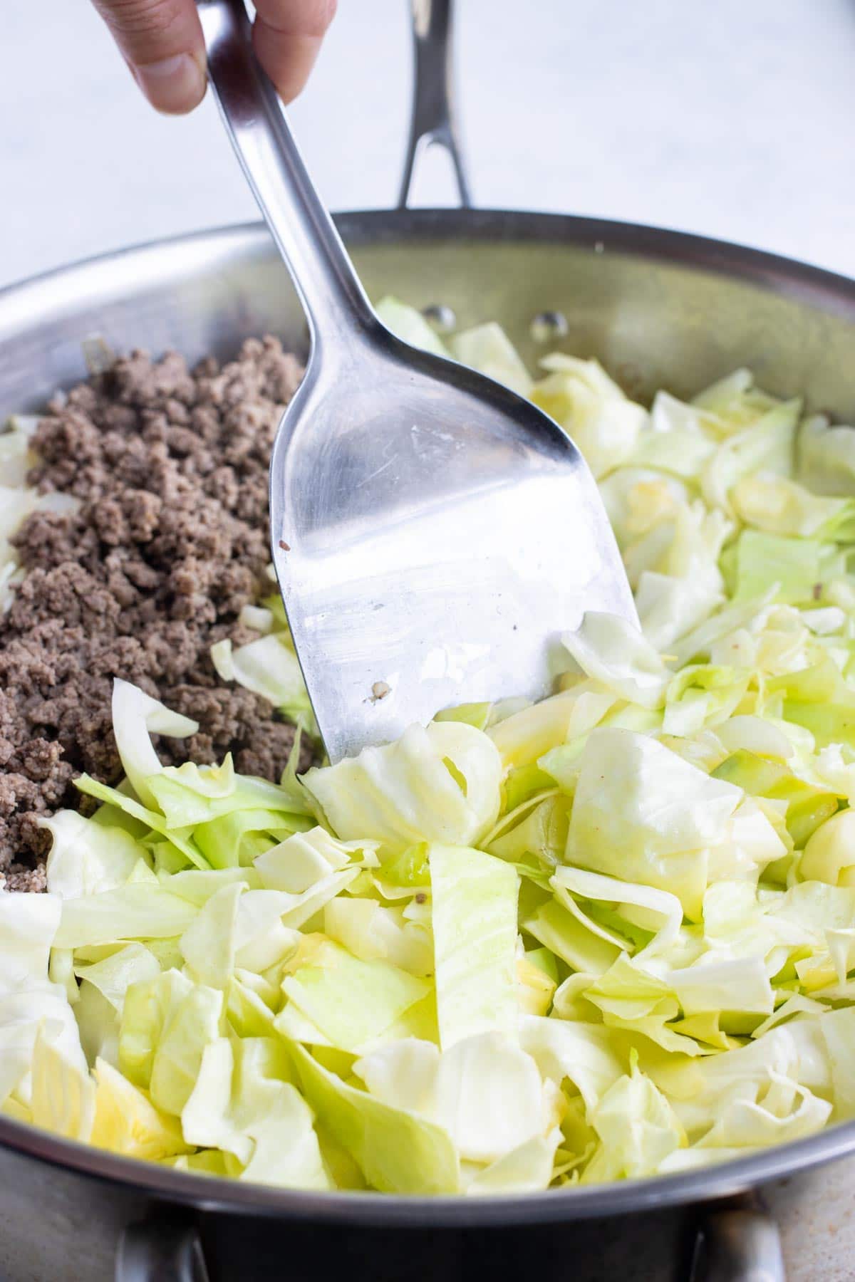 Cabbage is added to the cooked onions and ground beef.