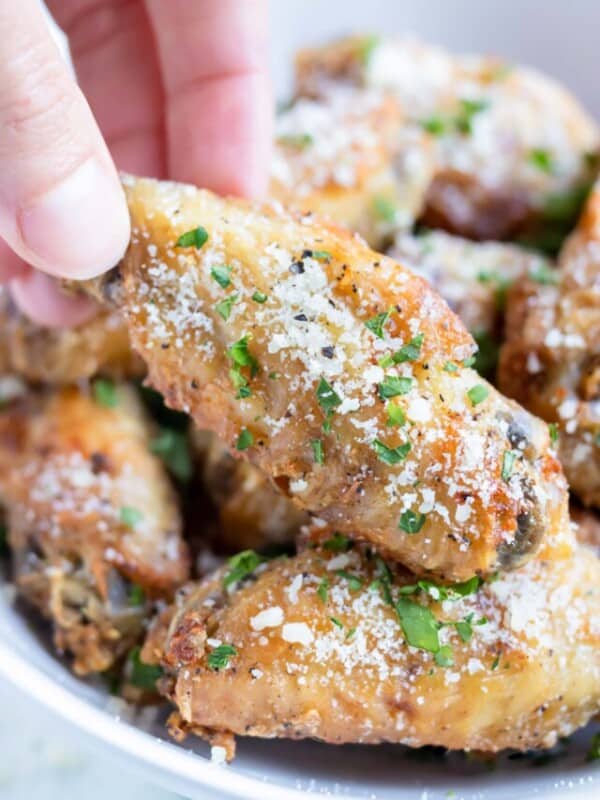 Crispy Garlic Parmesan Chicken Wings are in a serving bowl for a game day appetizer.