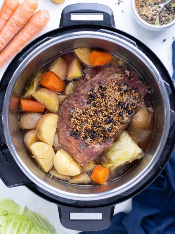 Corned Beef and Cabbage are shown in the pressure cooker with vegetables.