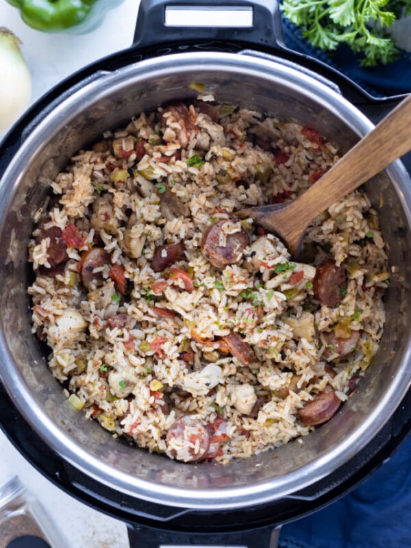 A bowl of traditional Instant Pot Jambalaya is served in a white bowl with a spoon.