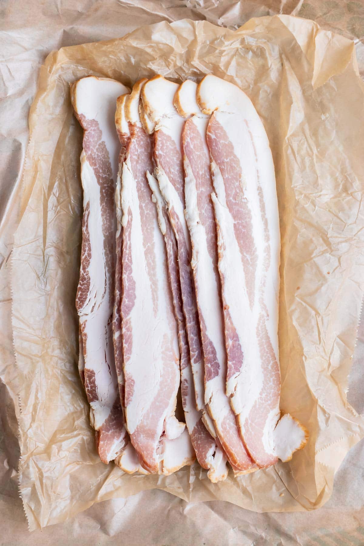 Thick-cut bacon strips are shown on butcher paper before being cooked in an air fryer.