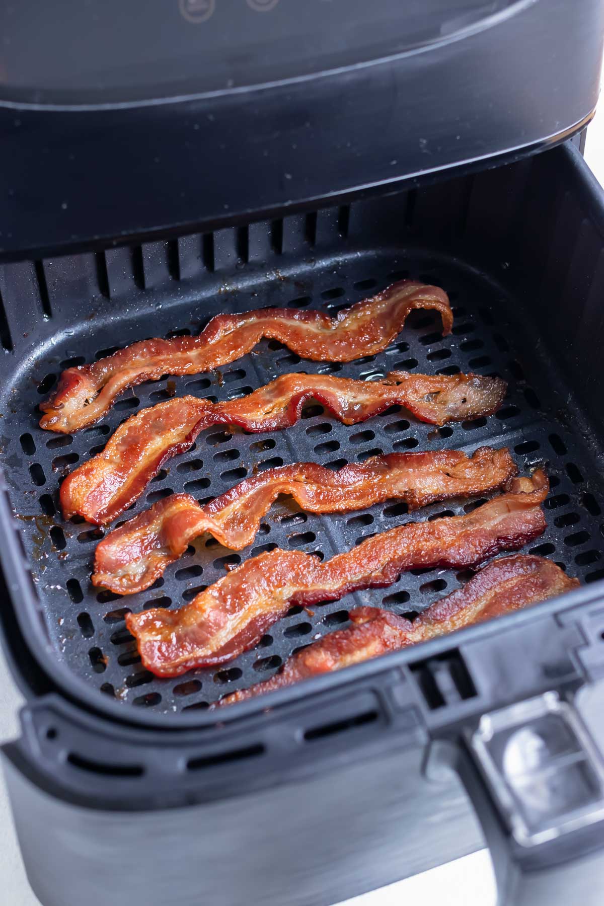 Bacon is cooked in the air fryer until crispy.
