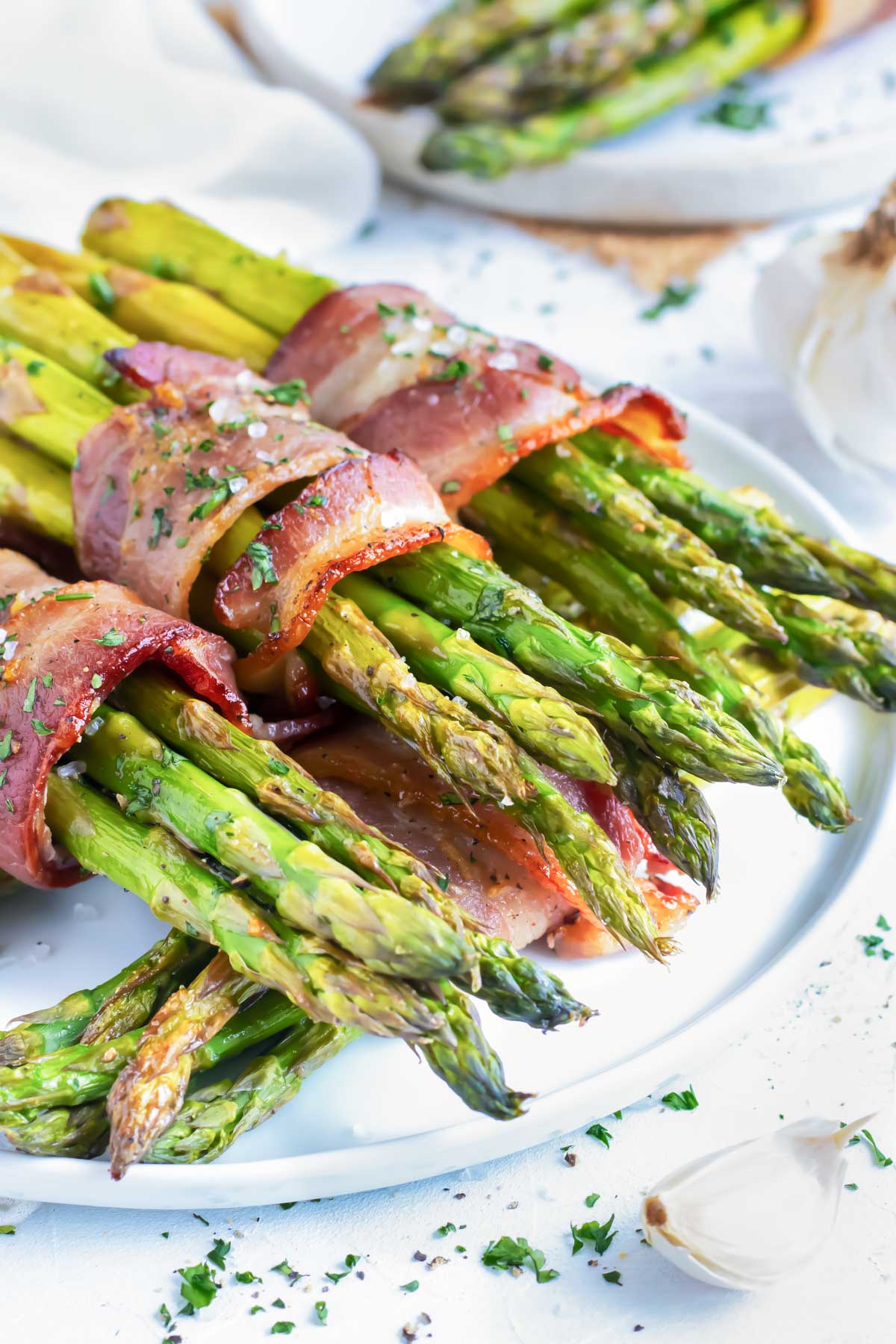 Bacon Wrapped Asparagus bundles on a white plate.
