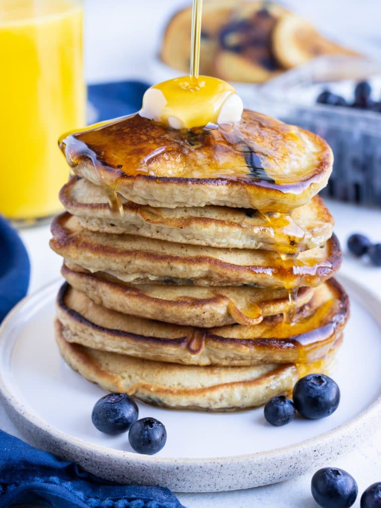 Syrup is poured over top of the blueberry pancakes.