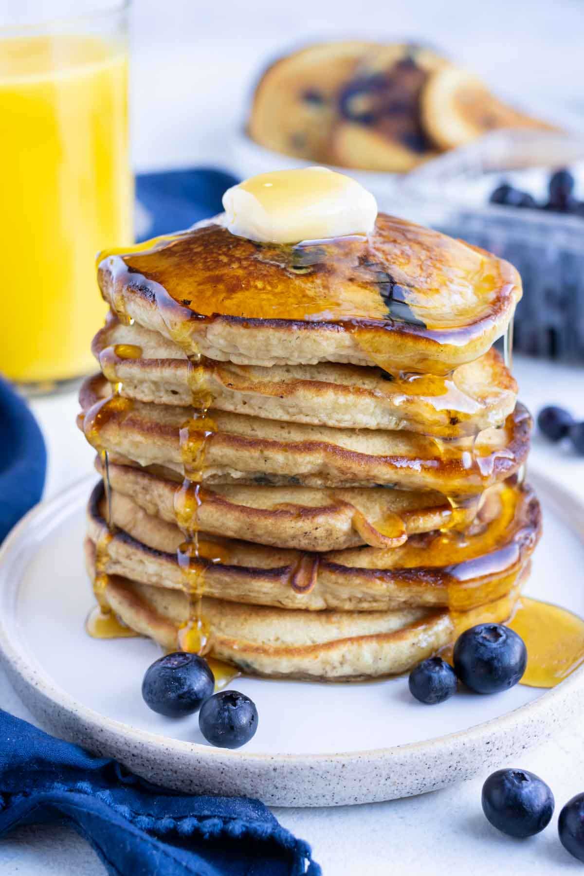 Butter and syrup are served on top of the blueberry pancakes.
