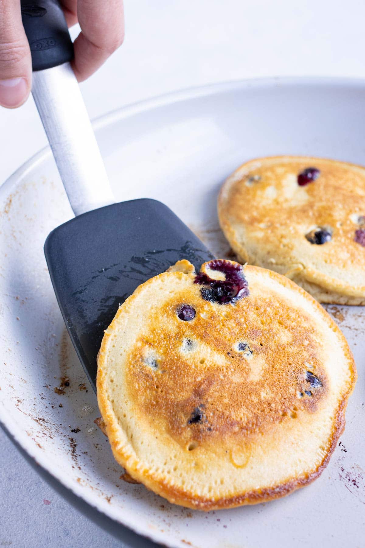 A spatula is used to flip the pancakes to cook each side.