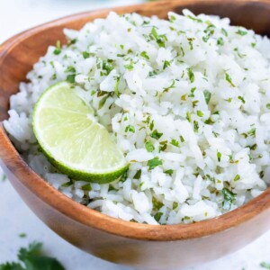 Fresh cilantro and a lime wedge is served with a bowl of cilantro lime rice.