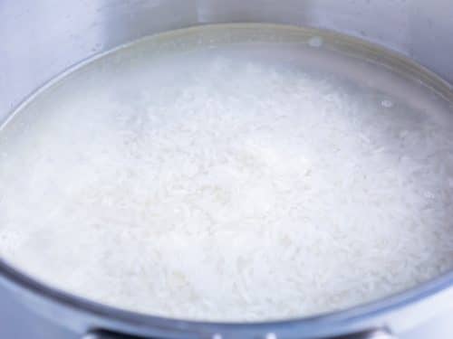 Rice is covered with water and boiled on the stove.