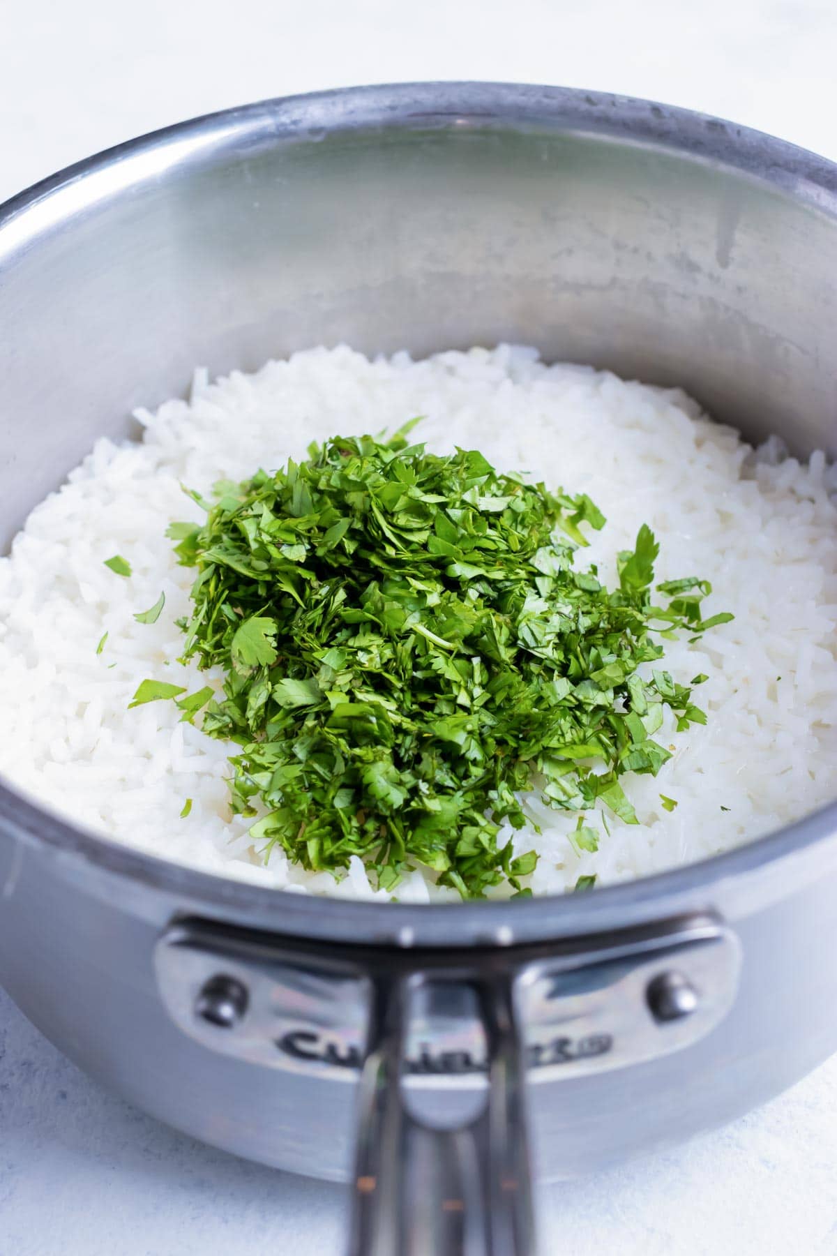 Chopped cilantro leaves are added to the cooked white rice.