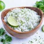 This easy cilantro lime rice recipe is served in a wooden bowl with fresh lime.