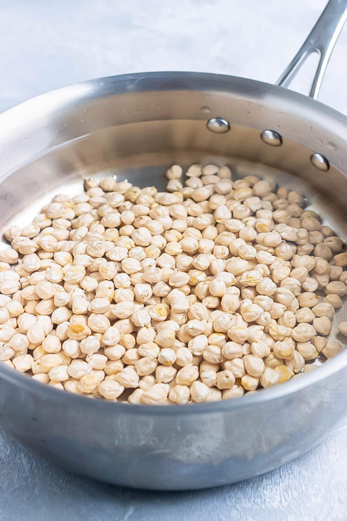 Dried chickpeas in a pot with water.