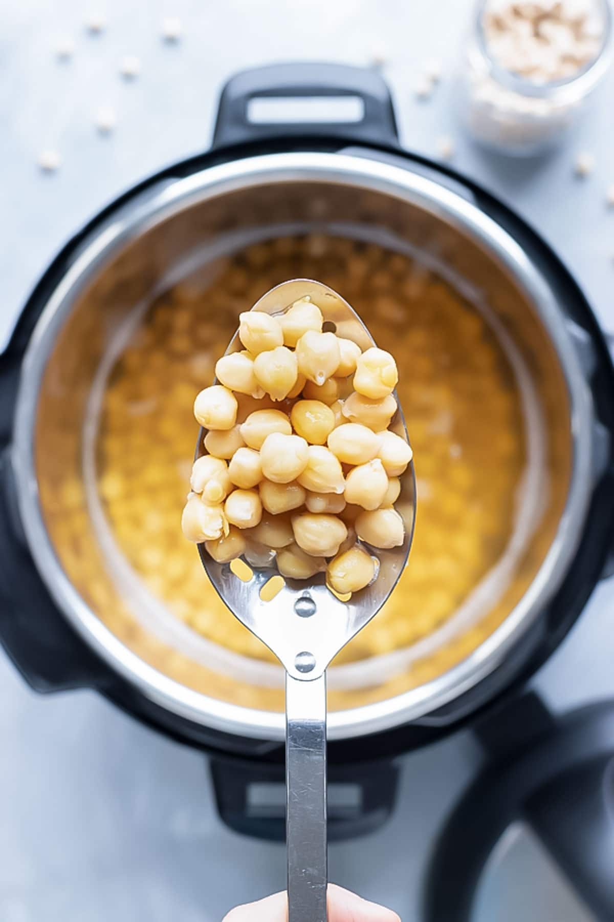A spoon full of chickpeas that have been cooked in an Instant Pot.