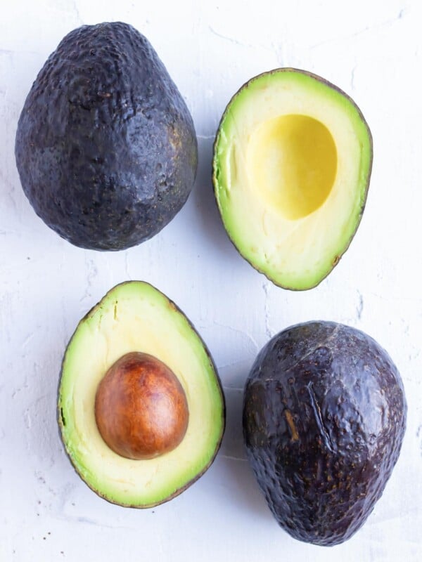 Two whole avocados and two avocado halves to show how to ripen avocados.