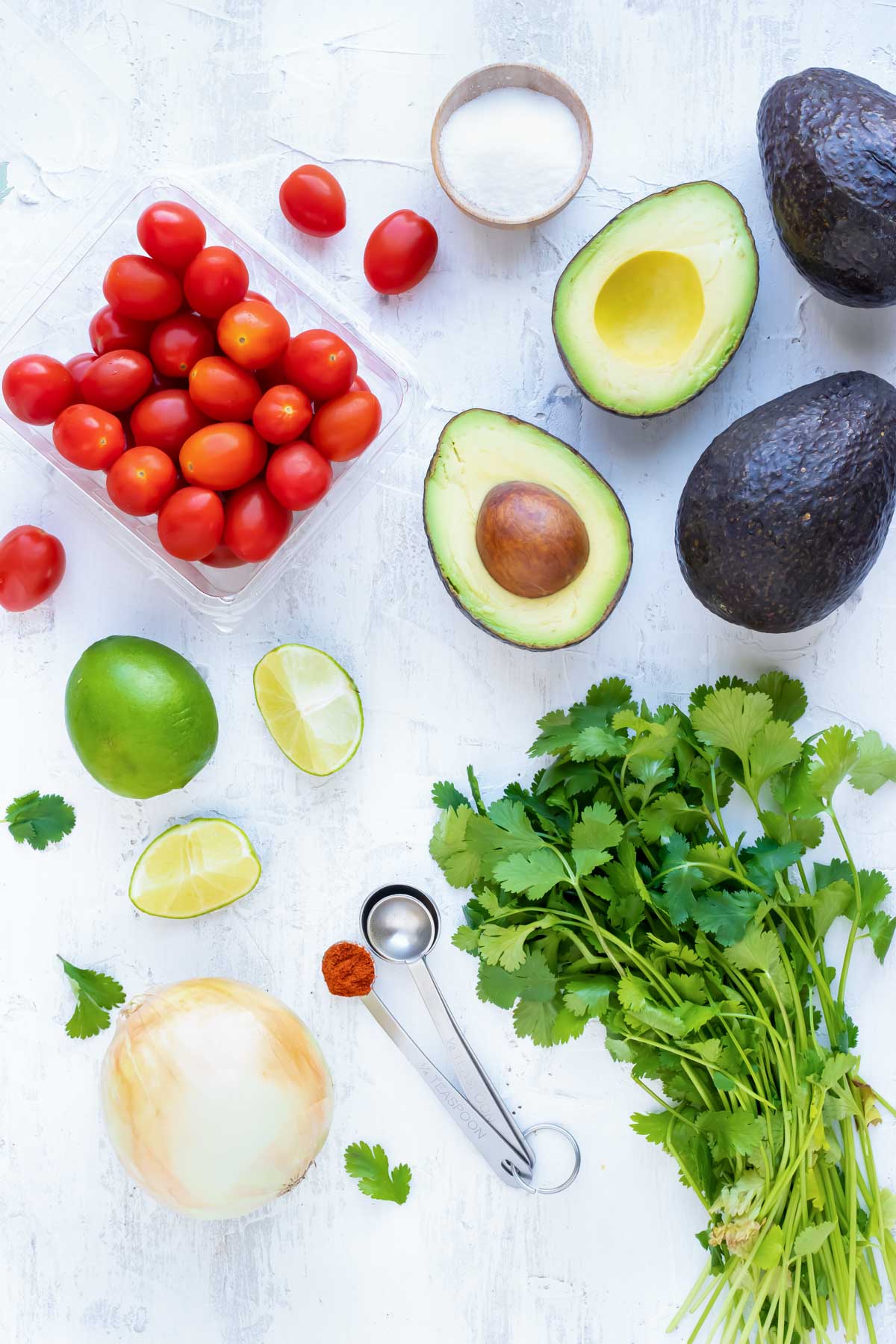 Avocados, tomatoes, onion, lime juice, and cilantro as guacamole ingredients.