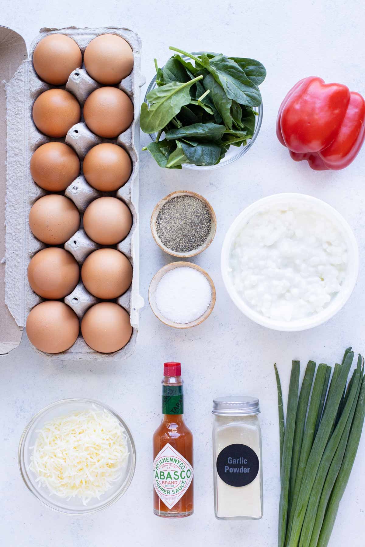 Egg whites, cottage cheese, shredded cheese, bell peppers, spinach, green onions, and seasonings are the ingredients for this recipe.