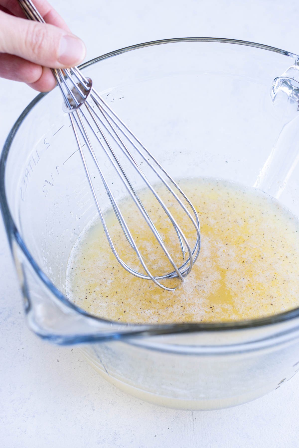 Eggs are whisked together with seasonings in a bowl.