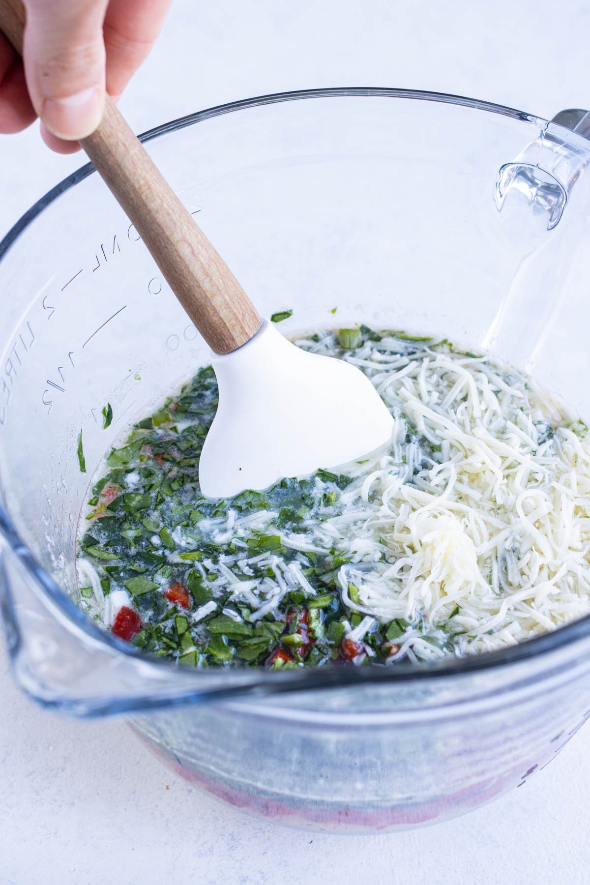 Chopped bell peppers, spinach and cheeses are added to the bowl.