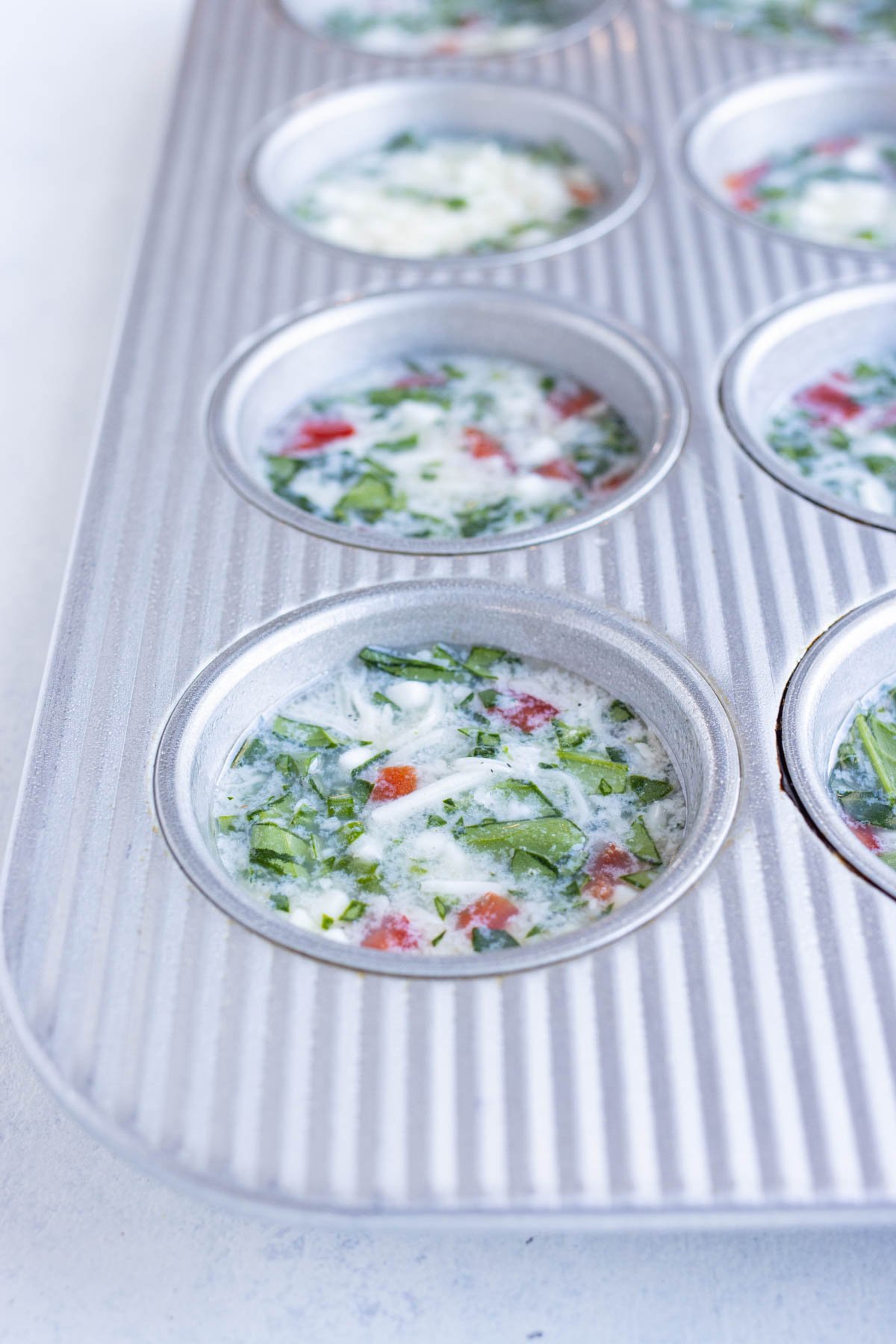 Egg mixture is added to the muffin pan.