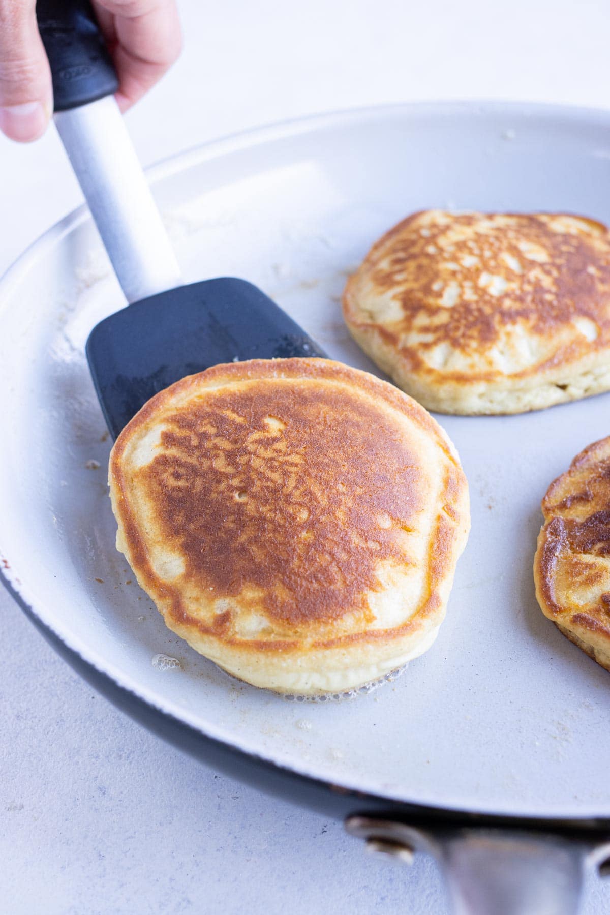 Pancakes are flipped with a spatula.