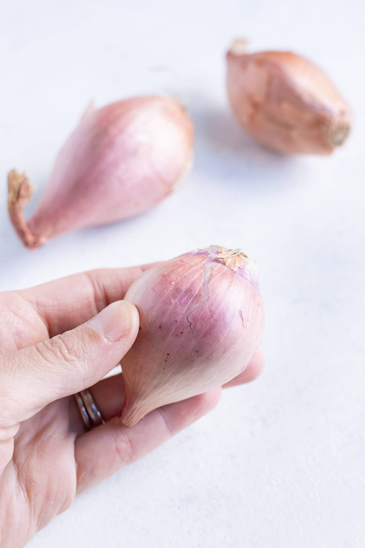 A shallot is picked up by a hand.