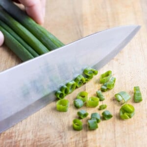 A sharp butcher's knife is used to finely chop the green onions.