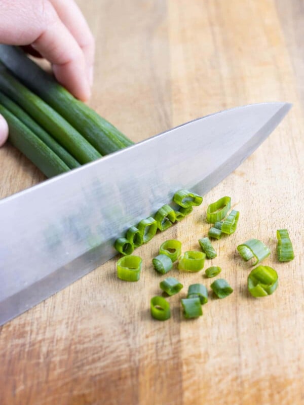 A sharp butcher's knife is used to finely chop the green onions.