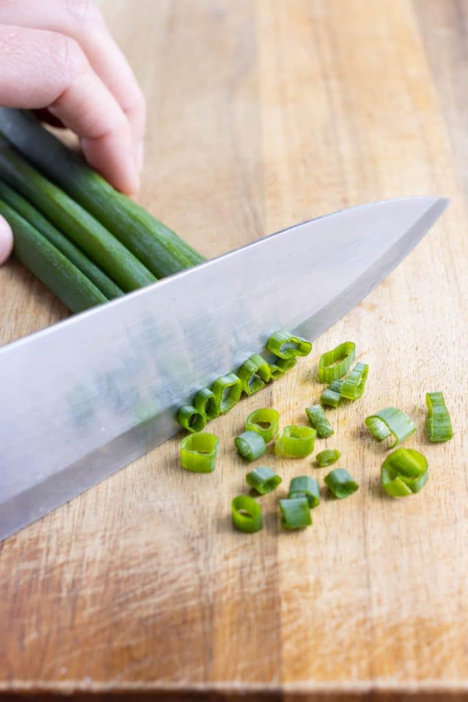 A sharp butcher's knife is used to finely chop the green onions.