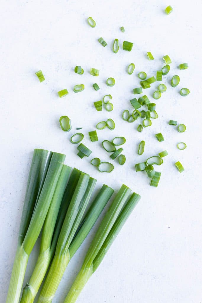 Whole and sliced green onions are shown on the counter.
