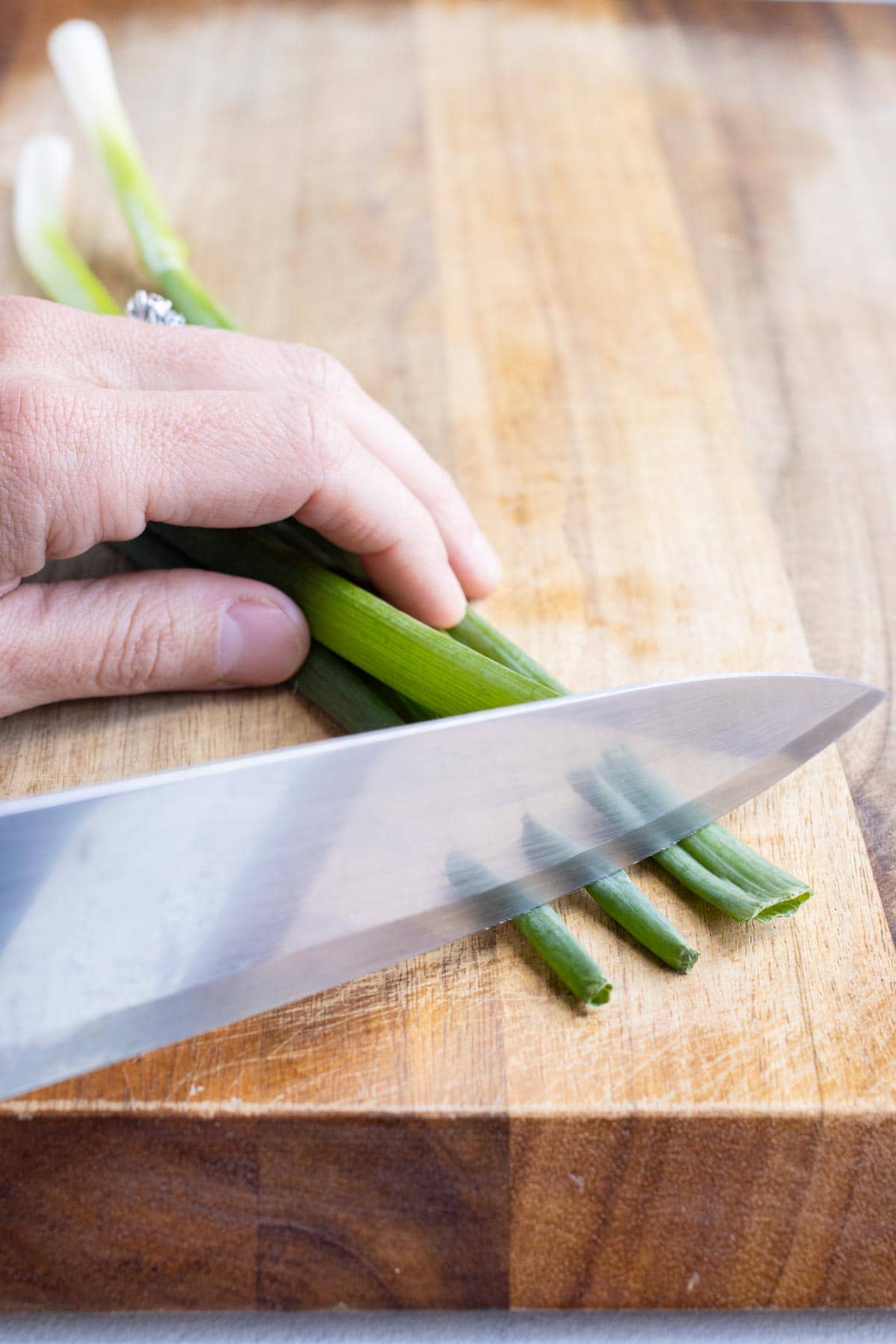 The tops of the green onions are trimmed with a knife.