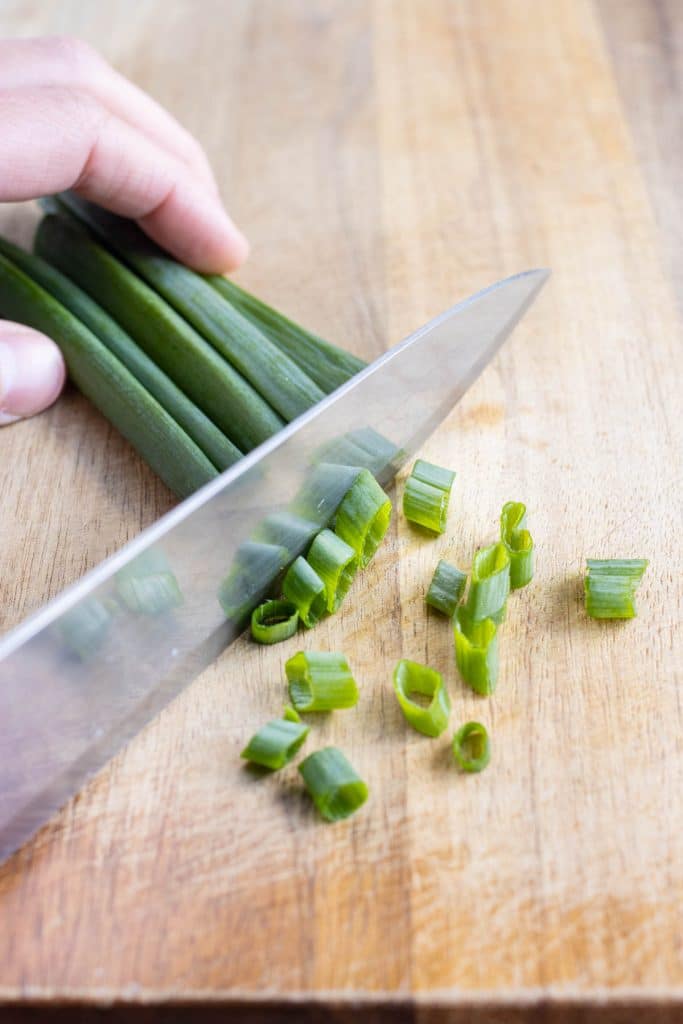 The ends of the green onions are sliced with a knife.