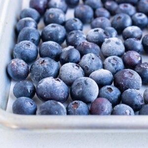 A layer of frozen blueberries is shown on the baking sheet.