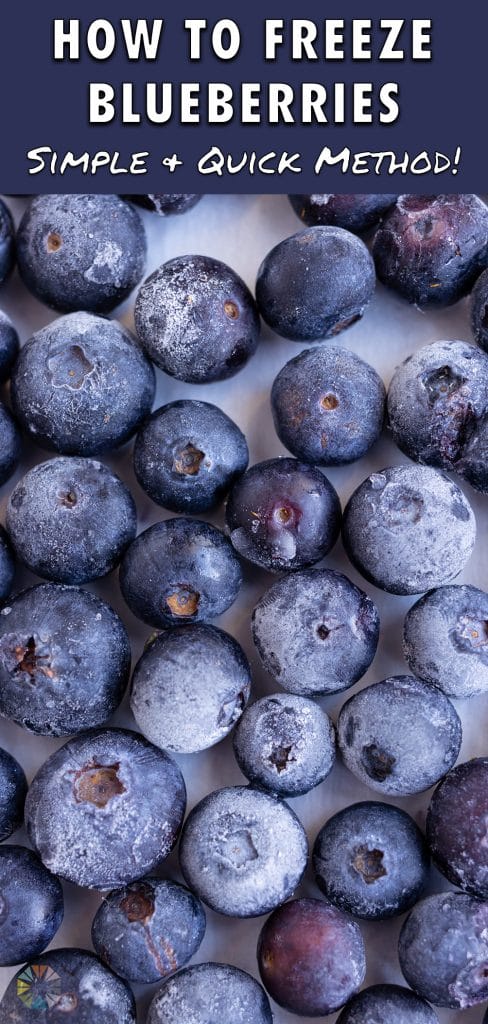 A baking sheet is covered with frozen blueberries.