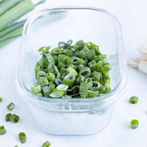 Frozen green onions in a Tupperware are shown on the counter.