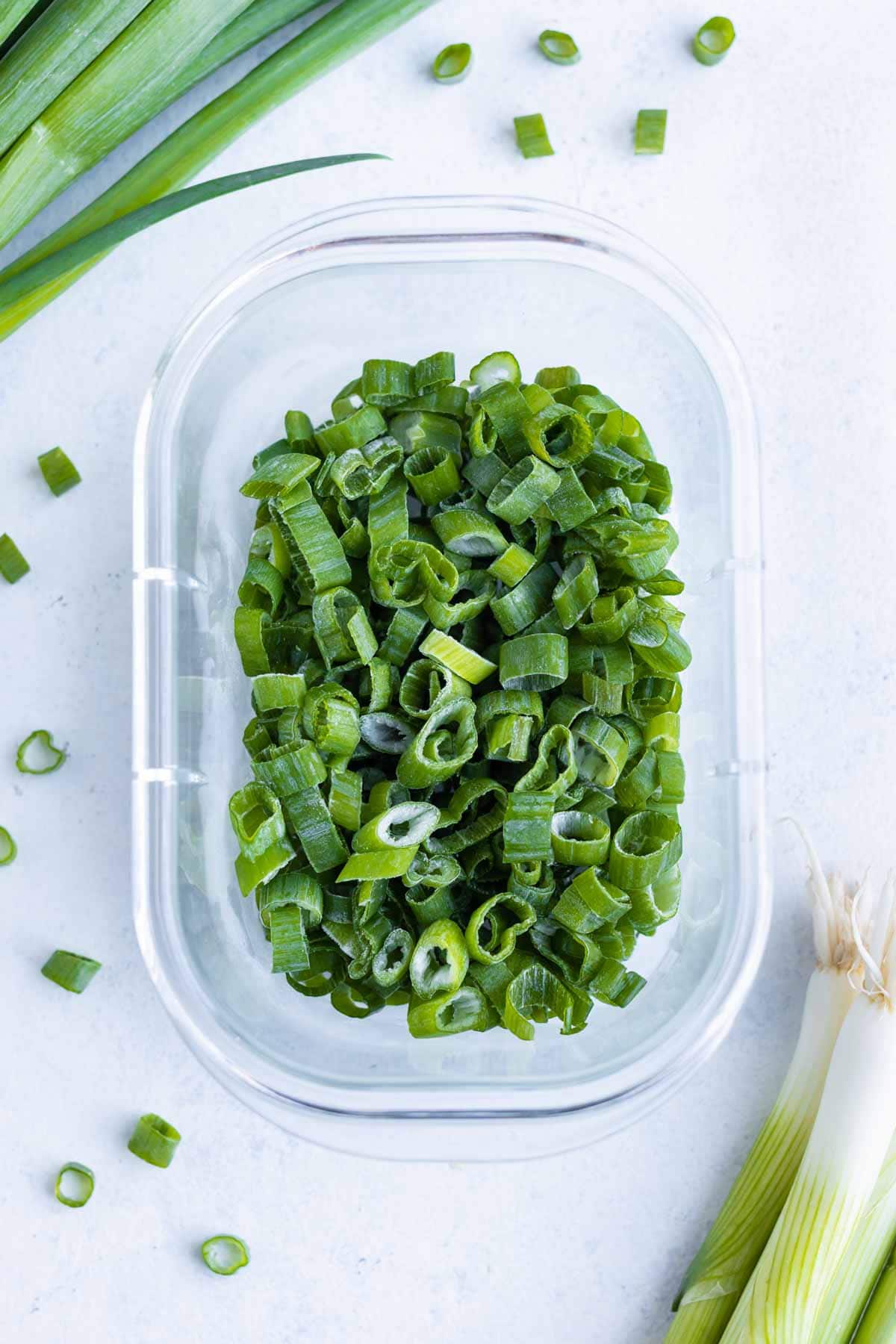 An overhead shot shows frozen green onions in a container.