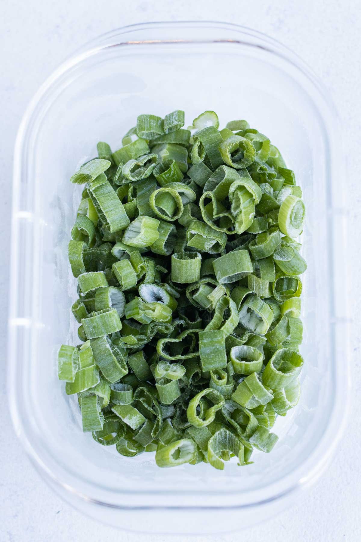 Frozen sliced green onions are stored in a container.