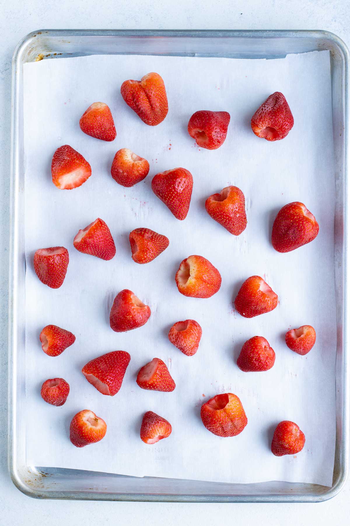 Prepared strawberries are laid flat to put in the freezer.