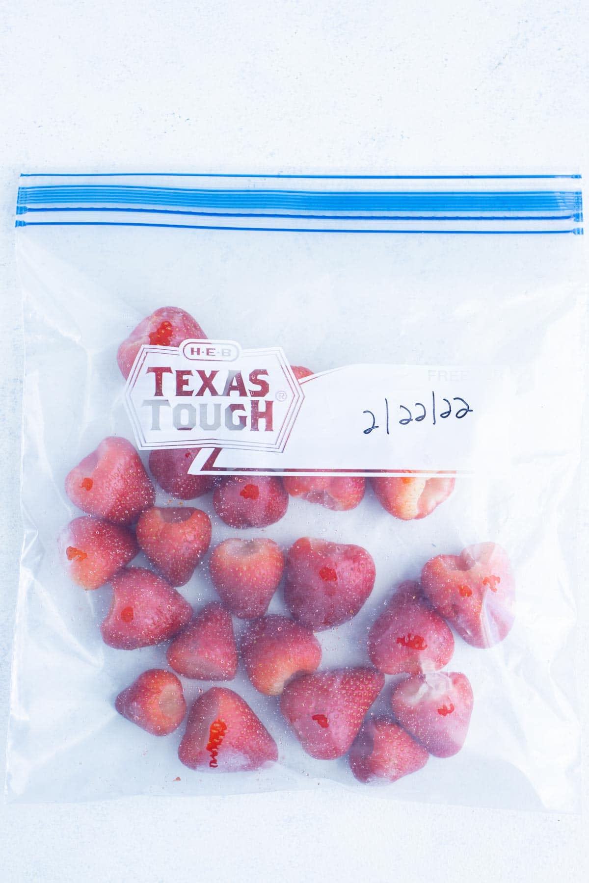 A freezer bag is filled with the pre-frozen strawberries.
