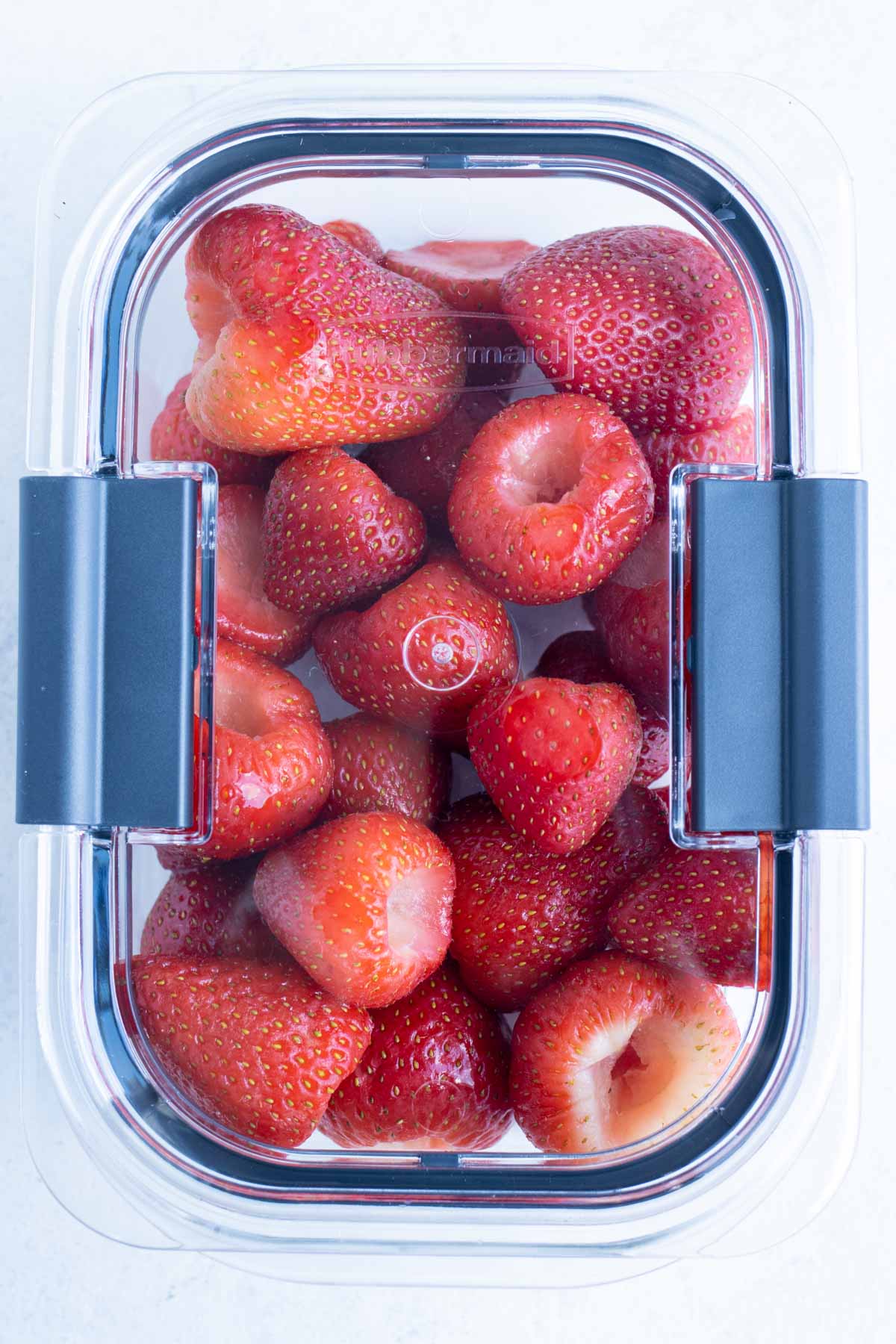 The lid is placed on the airtight container of frozen strawberries.