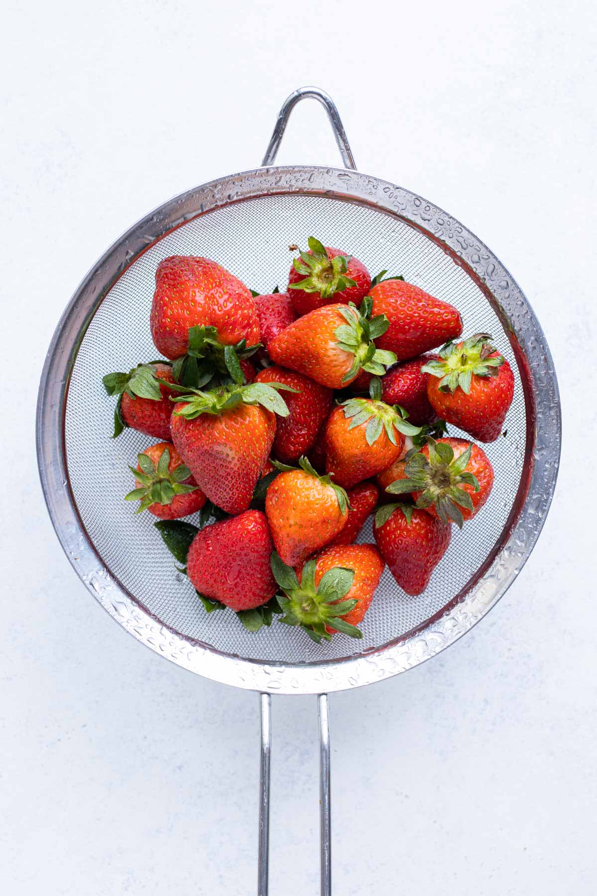 A strainer is used to wash and prepare the strawberries.