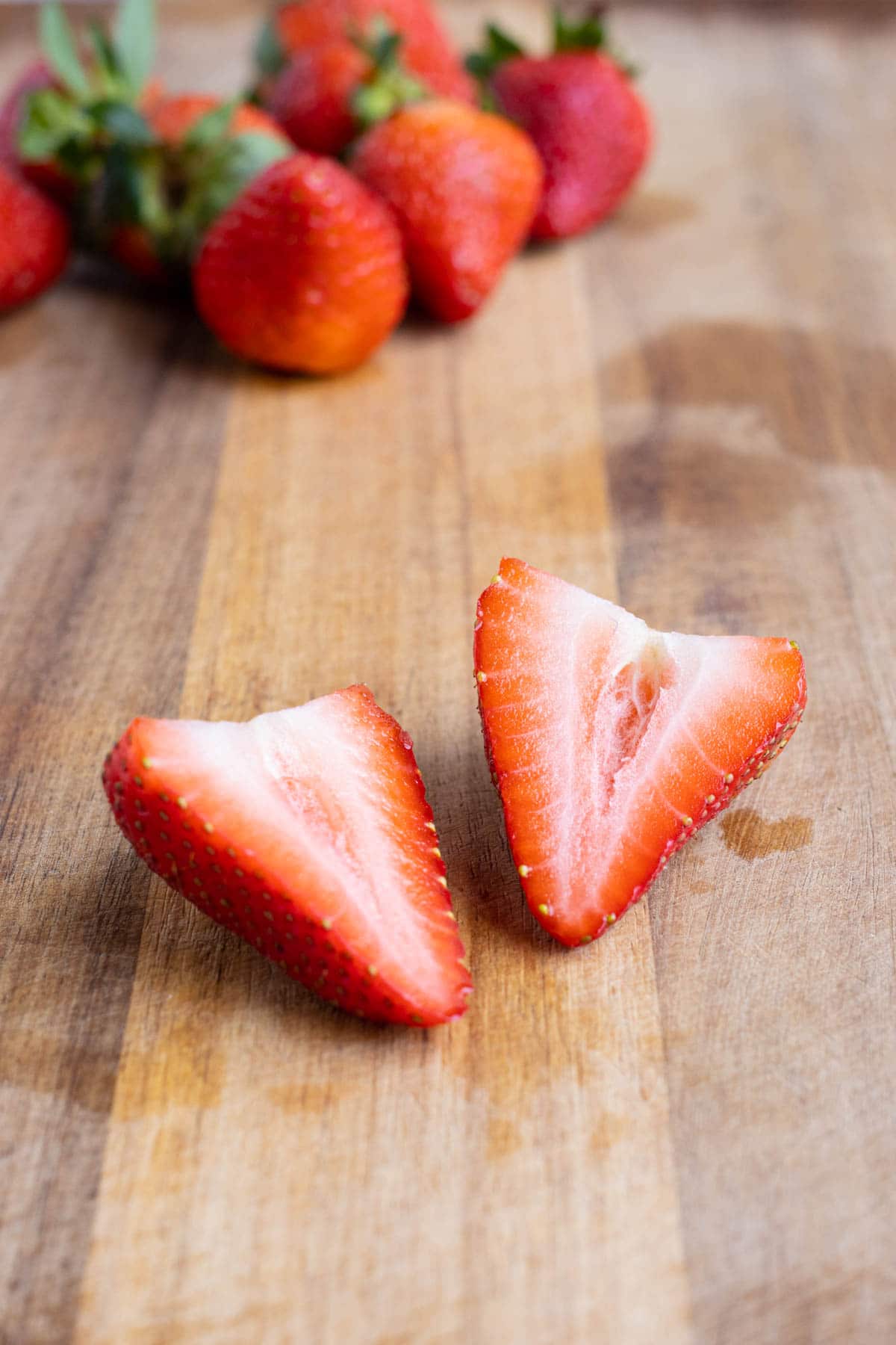 Strawberry halves are shown on a cutting board.